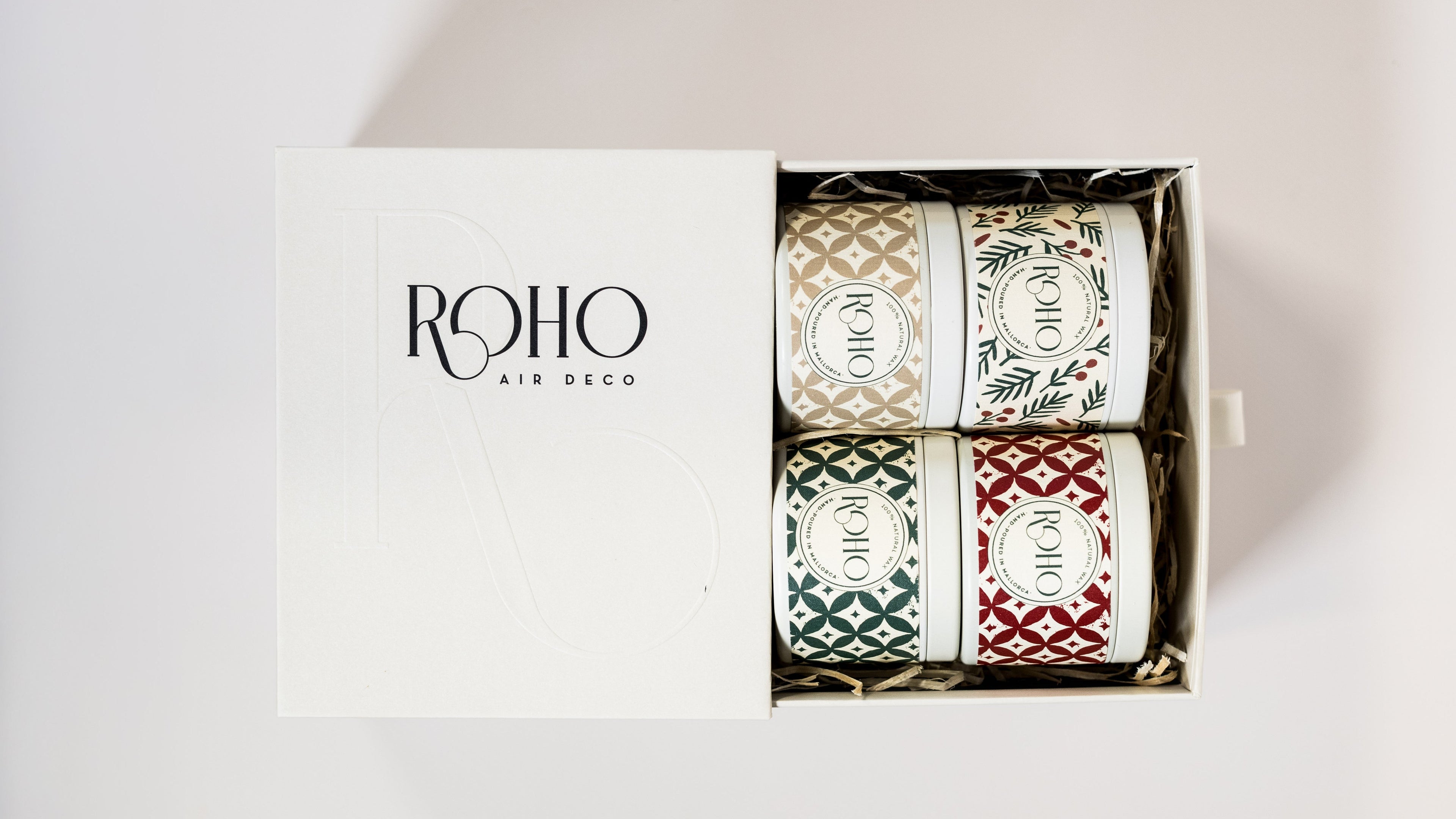 Set of four scented candles in decorative gift box with patterned designs labeled 'ROHO'. Christmas gift box, corporate gifts