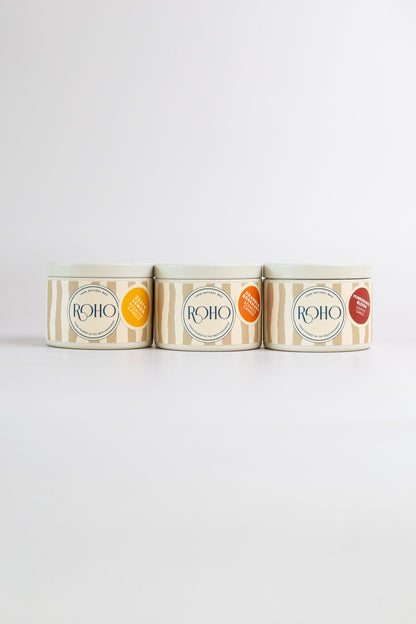 Three ROHO 90g candles in beige tins side by side – Zesty Lemon, Orange &amp; Rosemary and Pomegranate Bloom